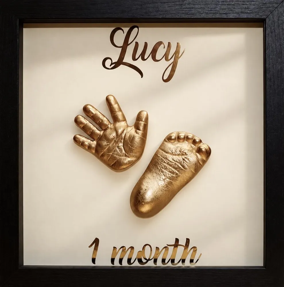 2D copper cast of a baby's hand and foot in a black frame, lettered Lucy, 1 month
